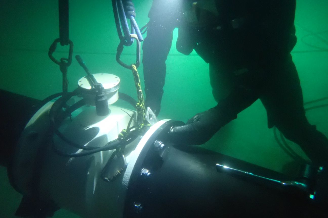Commercial diver installing flanged pipework underwater with rigging slings attached