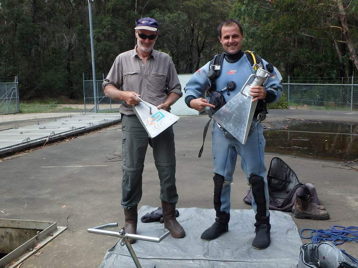 Crew comparing sediment scoops on a reservoir roof