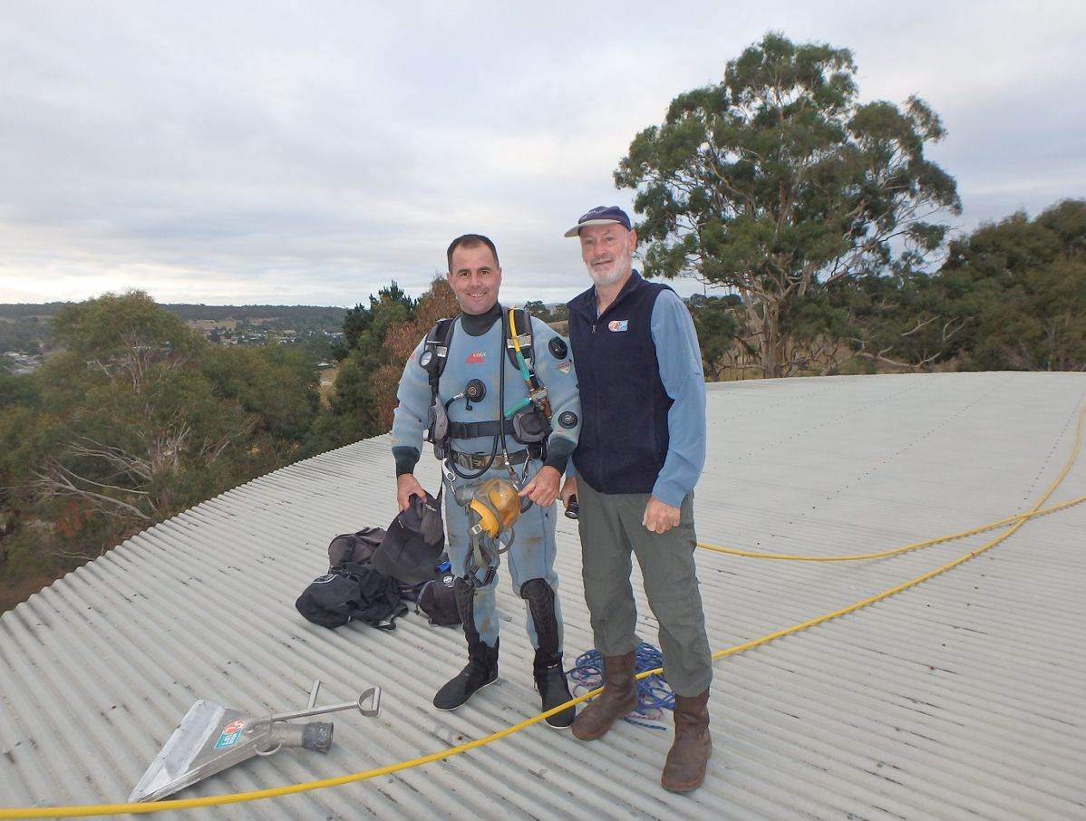 Two crew in harnesses on a tank roof with airline hose laid out