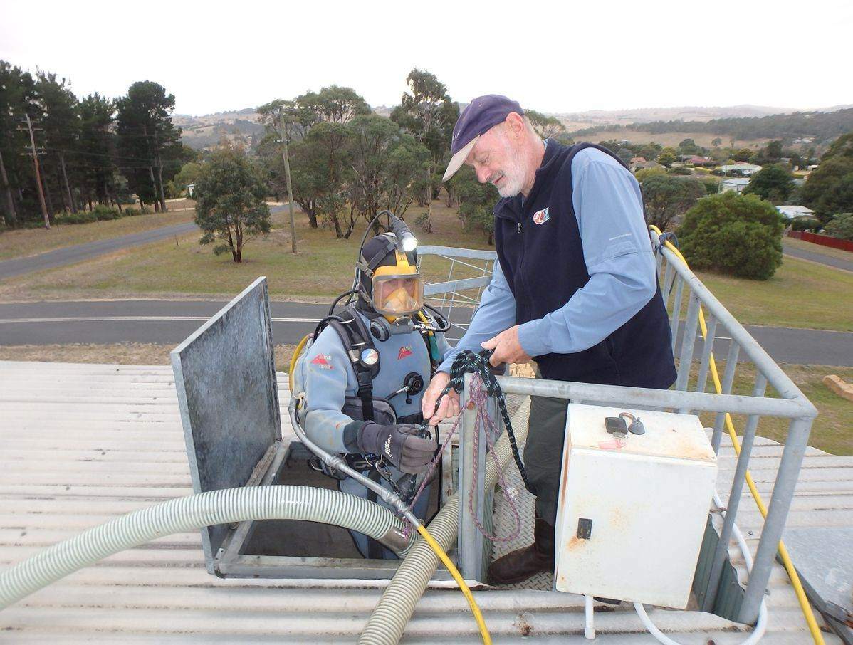 Diver and crew member preparing equipment on a reservoir access platform