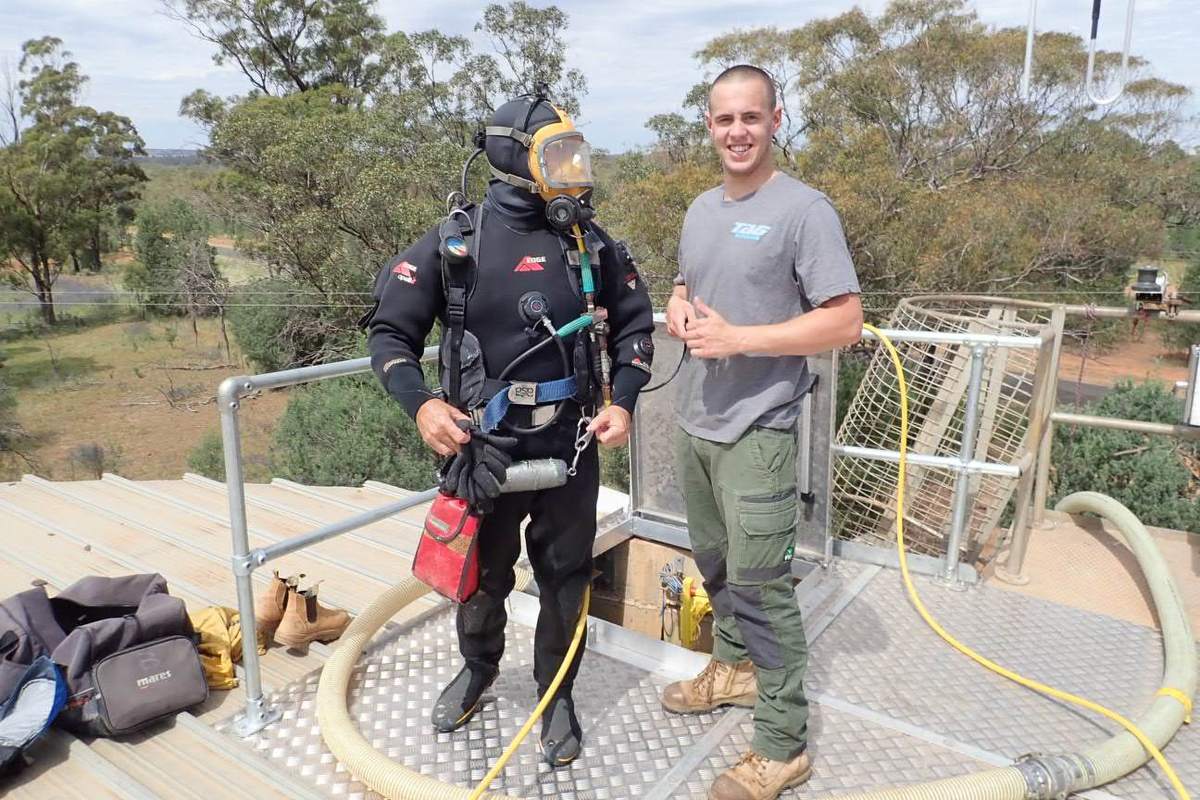 Diver and colleague at the handrail of a reservoir platform before a dive