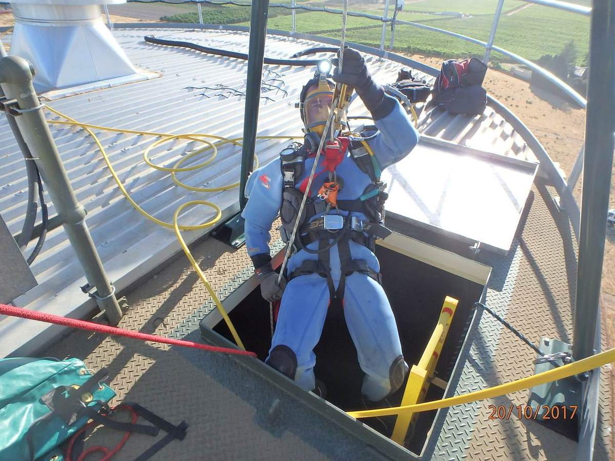 Diver in full face mask and harness being lowered through a reservoir roof hatch