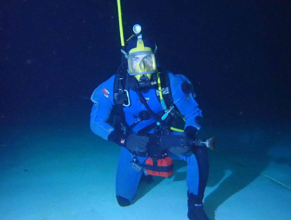 Diver in a blue drysuit swimming mid-water during an internal inspection