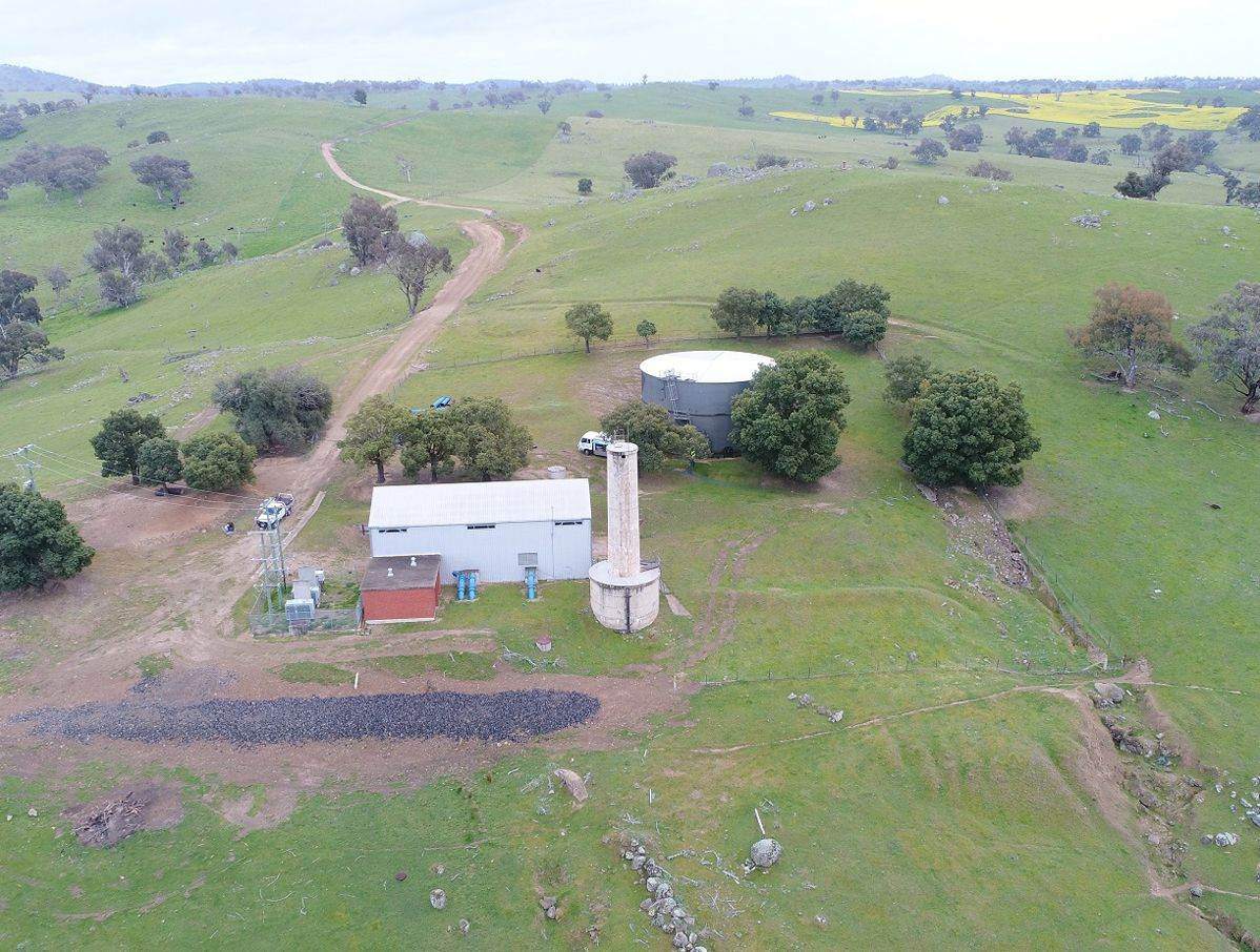 Aerial view of a rural water site with tank and shed