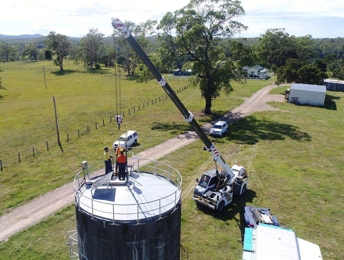 Aerial view of a rural tank site with a crane and truck alongside