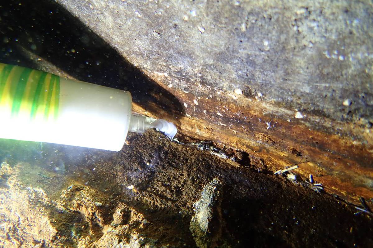 Leak detection probe held against corroded pipework underwater to trace a loss path
